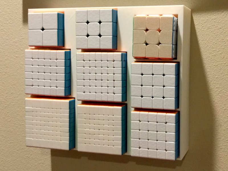 Nine twisting puzzle cubes, 2x2x2 through 9x9x9 (there are two 3x3x3s), in a wall-mounted box.
